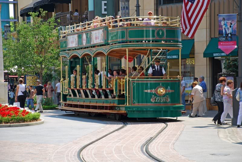 A green trolley is traveling down a city street.