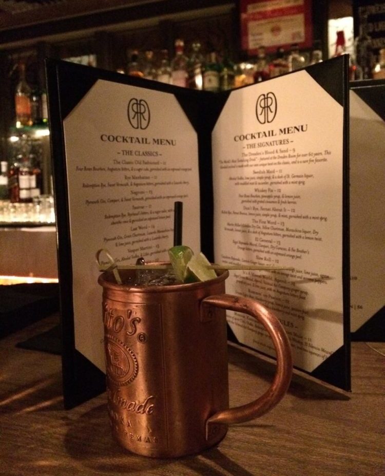 A moscow mule is sitting on a table next to a menu.