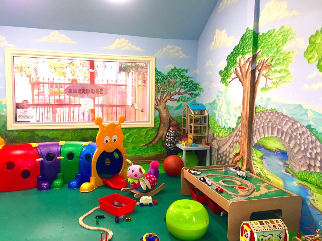 A children's playroom with toys and a mural.
