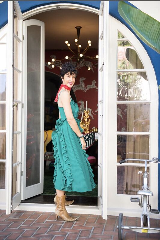 A woman in a green dress standing in front of a door.