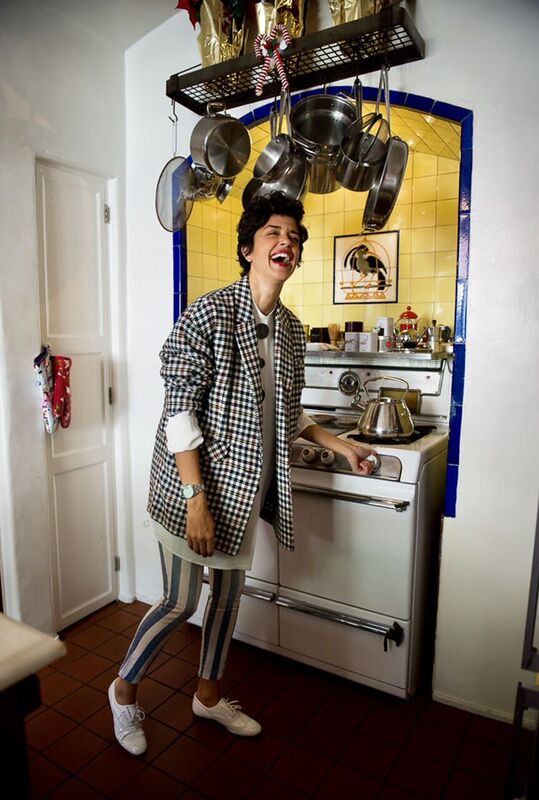 A woman standing in a kitchen with pots and pans.