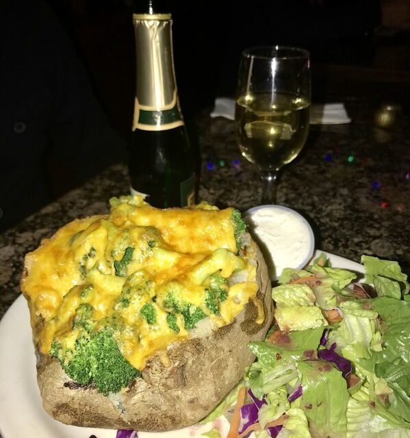A plate with broccoli, salad and a bottle of wine served at The Baked Potato Club.