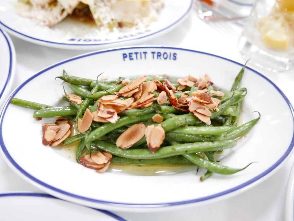 A Petit Trois plate with green beans and almonds on it.