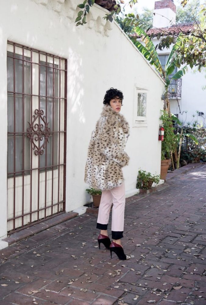 A woman wearing a leopard coat and pink pants.