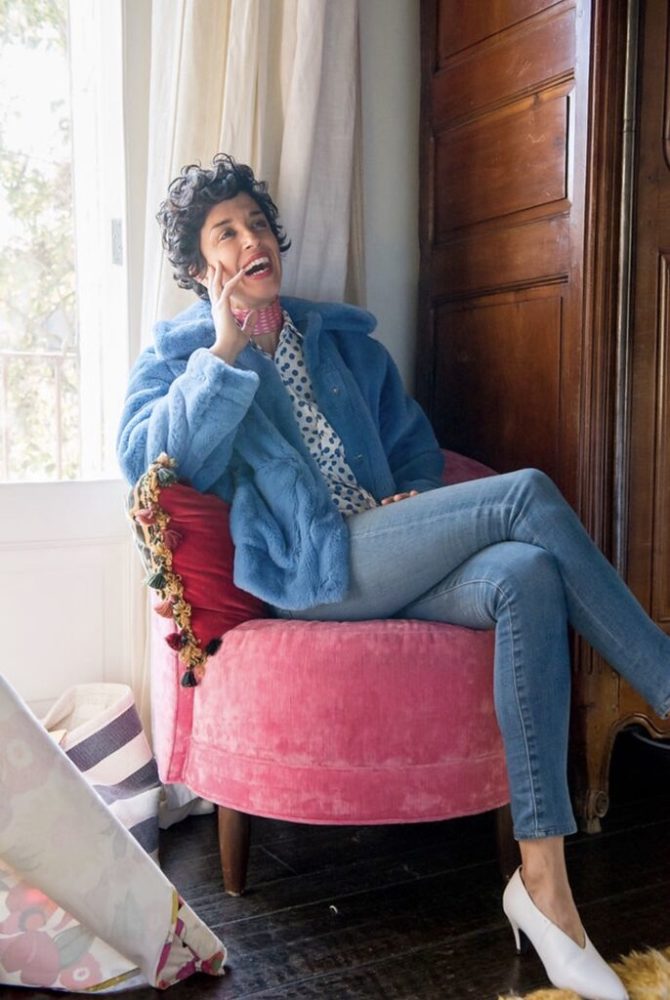 A woman sitting on a pink chair and talking on the phone.