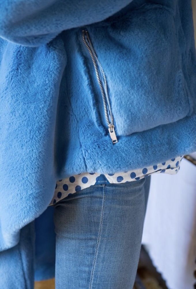 A woman wearing a blue fur jacket with polka dots.