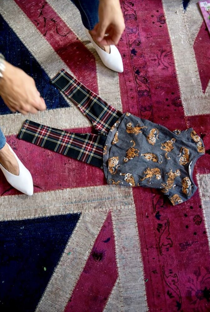A woman is laying a piece of clothing on a british flag rug.