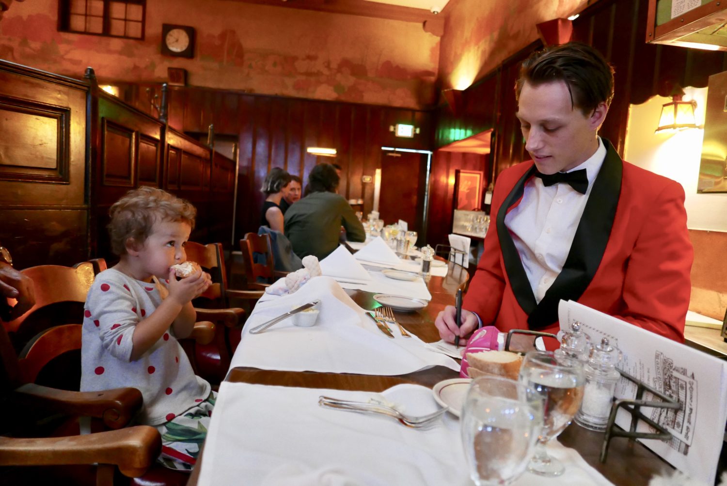 A man in a tuxedo sits at a table with a child at Musso & Franks.