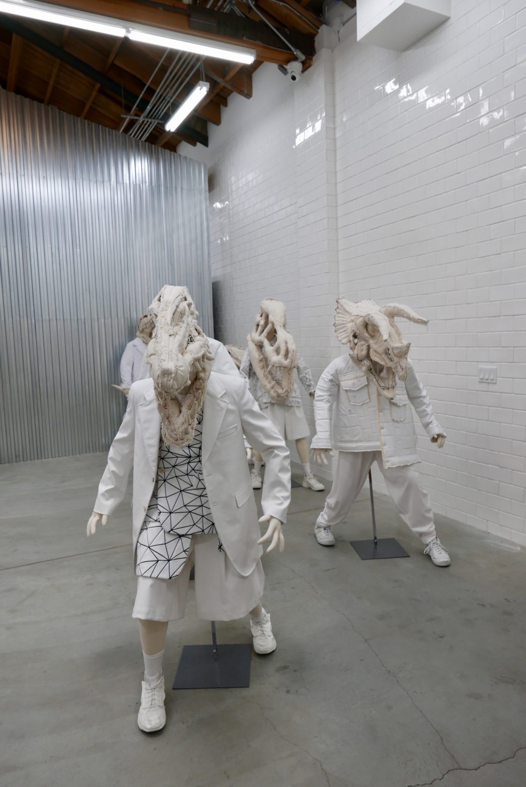 A group of people in white suits standing in Dover Street Market, a room.