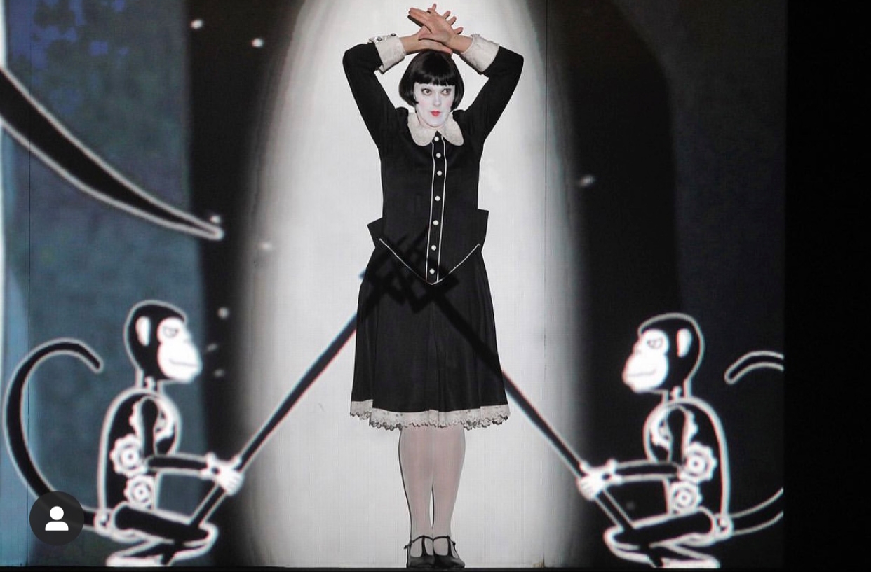 A woman dressed in black and white is standing on a stage.